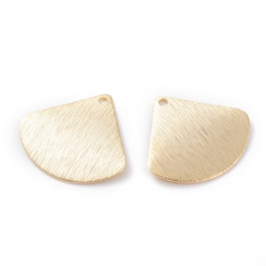 May include: Two gold-coloured metal half-circle shapes with a hole at the top. The shapes have a brushed finish.