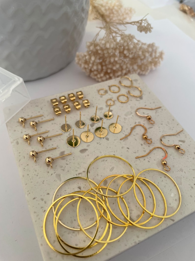 May include: A collection of gold-toned earring findings and hoops. The set includes earring posts, earring wires, and hoops of various sizes.