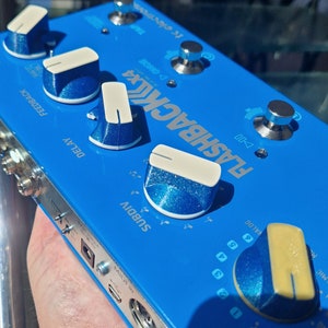 Könnte beinhalten: Ein blaues E-Gitarren-Effektpedal mit dem Text "FLASHBACKX4" und Knöpfen mit den Beschriftungen "SUBDIV", "DELAY", "FEEDBACK" und "VALOG".