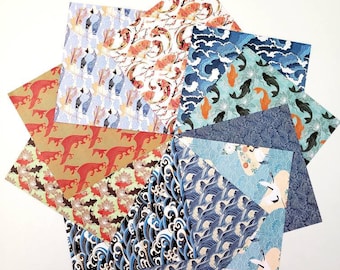 Puede incluir: Un conjunto de ocho hojas de papel de origami con varios diseños de inspiración japonesa, incluyendo peces koi, olas y grullas. Los papeles son en tonos de azul, rojo, naranja y blanco.