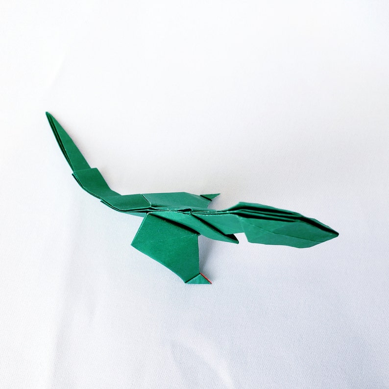 May include: A green origami lizard with a long tail and a pointed head.