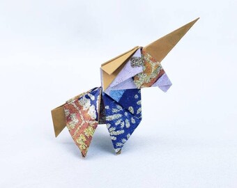 Puede incluir: Un unicornio de origami azul y marrón con un cuerno marrón. El unicornio está hecho de papel estampado.