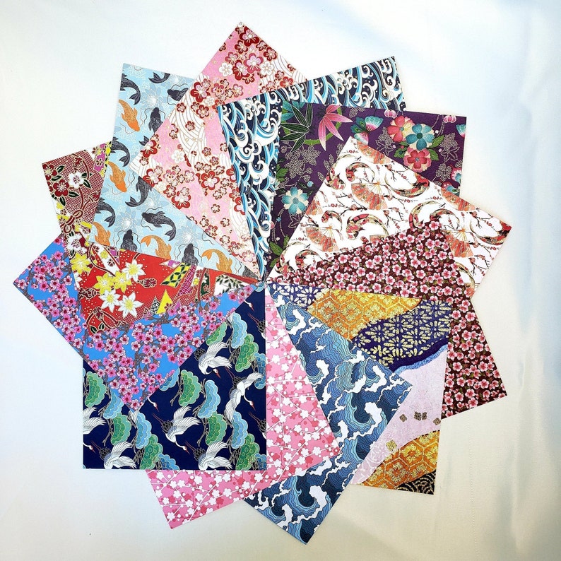 May include: Assortment of 15 origami paper sheets with various Japanese-inspired patterns, including cherry blossoms, waves, and fish. The paper is in shades of pink, blue, red, gold, and white.
