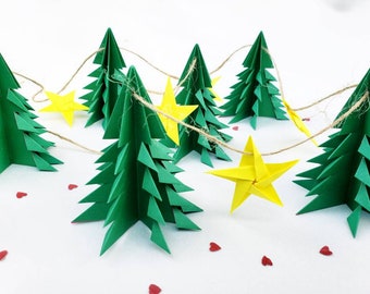 Puede incluir: Una guirnalda que presenta varios árboles de Navidad de papel origami verde en tres dimensiones y estrellas de papel origami amarillo brillante ensartadas en un cordel marrón fino, con pequeños corazones de papel rojo.