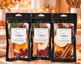 May include: Three black stand-up pouches containing simmer pot kits. Each label reads Soy Creations Studio Cozy Vibes Simmer Pot Kit. The clear windows reveal dried orange slices, cinnamon sticks, star anise, cranberries, and cloves.