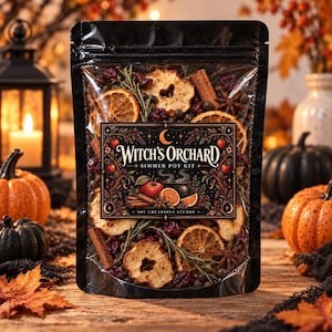 May include: A clear plastic pouch containing a Witch's Orchard simmer pot kit, filled with dried apple slices, orange wheels, cinnamon sticks, star anise, rosemary sprigs, and cranberries, featuring a label with the text Witch's Orchard.