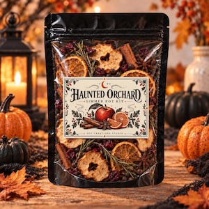 May include: A clear plastic pouch containing a Haunted Orchard simmer pot kit with dried apple slices, orange wheels, cinnamon sticks, star anise, cranberries, and rosemary. The label features an illustration of an apple and orange slices.