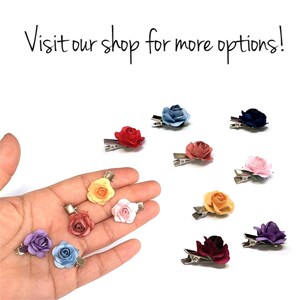 May include: Assortment of ten fabric flower hair clips in various colors, including blue, red, yellow, pink, purple, and orange. The clips are displayed on a hand and a white background.