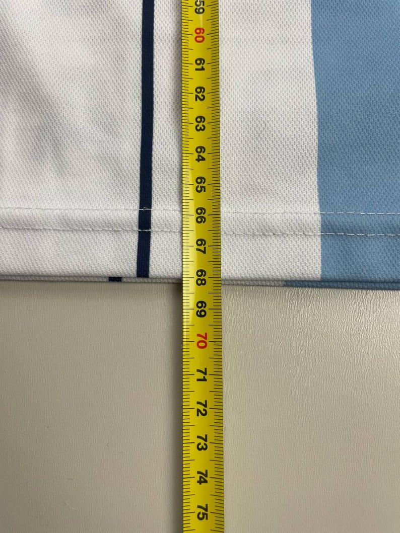May include: Close-up of a white and light blue fabric with a dark blue stripe. A yellow measuring tape shows measurements from 59 to 75 inches.