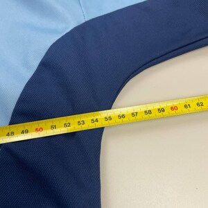 May include: A light blue and navy blue garment with a yellow measuring tape laid across it. The tape reads from 48 to 62 inches. The garment appears to be made of a textured fabric.
