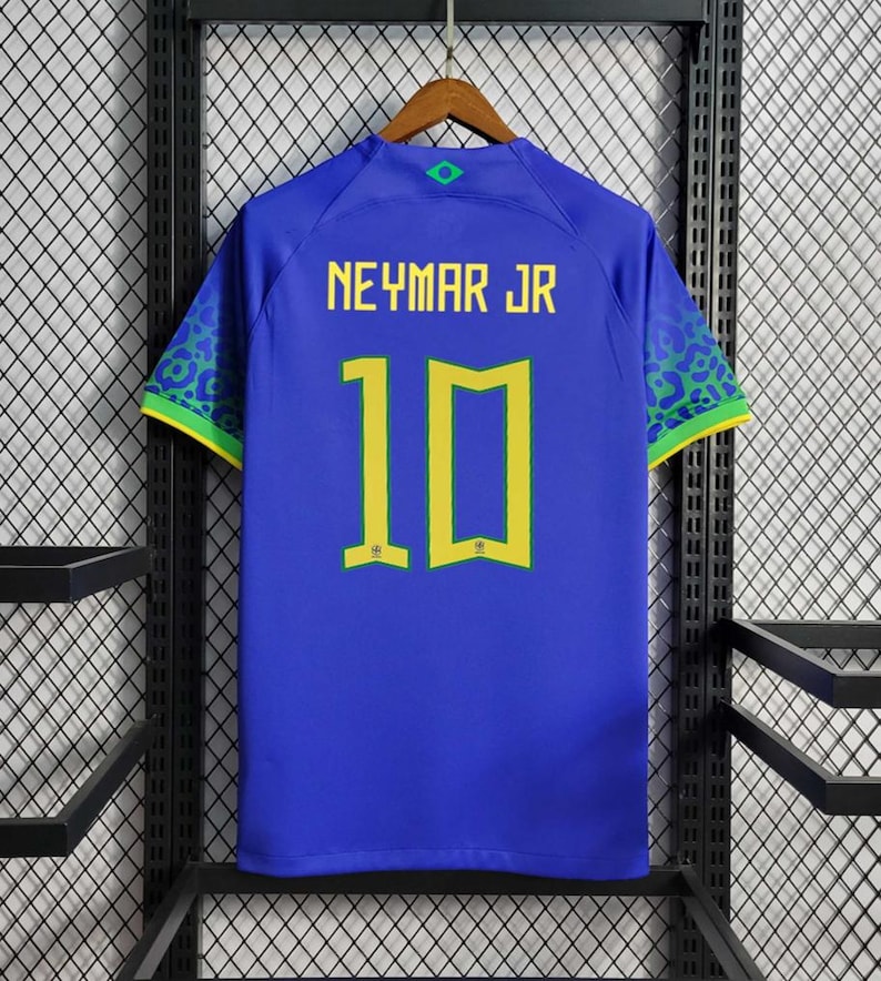 Może przedstawiać: Niebieska koszulka piłkarska z ż&oacute;łtymi i zielonymi akcentami. Na plecach koszulki nadrukowano nazwisko "NEYMAR JR" i numer "10" w kolorze ż&oacute;łtym.