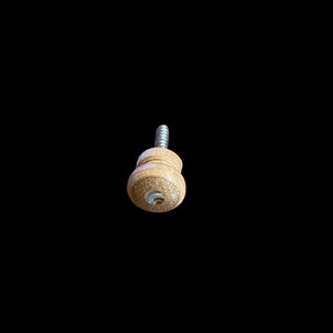 May include: A wooden knob with a screw, the knob is light brown and has a small hole in the center.