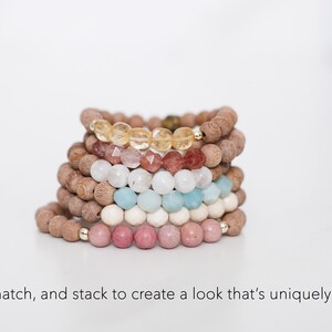 May include: A stack of six beaded bracelets featuring brown wooden beads and faceted gemstone beads in yellow, pink, white, light blue, and cream, with small gold-toned metal accents. The text below reads: Mix, match, and stack to create a look that's uniquely yours.
