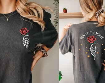 May include: A dark gray oversized t-shirt with a skeleton hand holding a red rose on the front and the text "RUN LITTLE MOUSE" with a skeleton hand holding a red rose and gold stars on the back.
