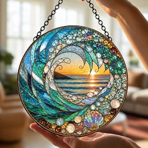 May include: A circular stained glass suncatcher featuring a mosaic ocean wave design with shades of blue, teal, and white glass pieces. The center depicts a sunset over the sea, accented with small glass beads, shells, and a metal hanging chain.