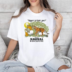 May include: White t-shirt with a cartoon image of Winnie the Pooh and Tigger. The text "Tigger, is that you?" and "Disney's Animal Kingdom" are printed on the shirt.