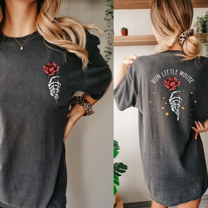 Peut inclure: Un t-shirt surdimensionn&eacute; gris fonc&eacute; avec une main squelettique tenant une rose rouge sur le devant et le texte "Run Little Mouse" avec une main squelettique tenant une rose rouge et des &eacute;toiles dor&eacute;es au dos.