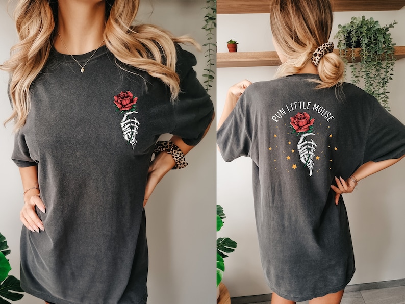 Peut inclure: Un t-shirt surdimensionn&eacute; gris fonc&eacute; avec une main squelettique tenant une rose rouge sur le devant et le texte "Run Little Mouse" avec une main squelettique tenant une rose rouge et des &eacute;toiles dor&eacute;es au dos.