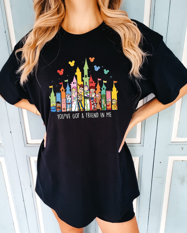 May include: Black t-shirt with a colorful graphic of Toy Story characters in front of a stylized Disney castle. The text "You've got a friend in me" is printed below the graphic.