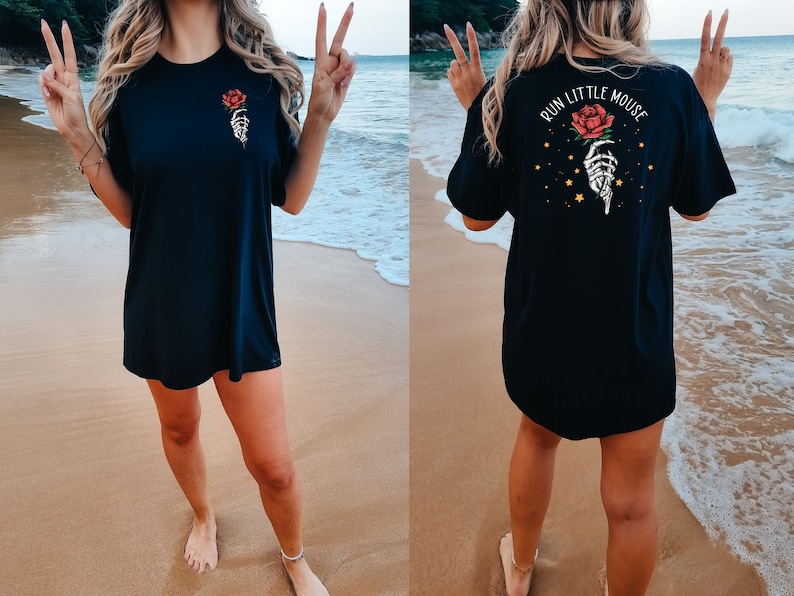 Peut inclure: T-shirt noire surdimensionn&eacute;e avec un motif de main squelettique tenant une rose rouge. Le dos du t-shirt dit "Run Little Mouse" avec un motif de main squelettique tenant une rose rouge et des &eacute;toiles dor&eacute;es.