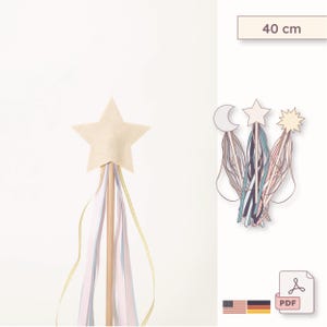 May include: A beige star-shaped wand with pastel ribbons and a wooden handle. The wand is approximately 15.7 inches long. A drawing of celestial shapes with ribbons is also shown.
