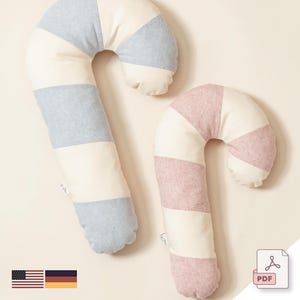 Puede incluir: Dos almohadas de bastón de caramelo a rayas, una en azul y blanco y otra en rosa y blanco. Las almohadas están hechas de tela suave y son perfectas para acurrucarse.