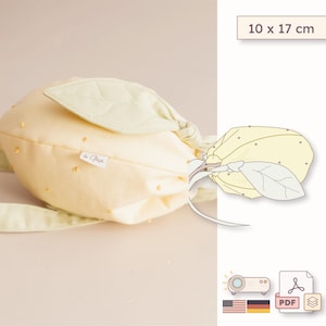 May include: A pale yellow fabric pouch shaped like a lemon, featuring a light green leaf accent, small yellow dot details, and a white brand tag. The pouch measures 10 x 17 cm. A line drawing of the lemon pouch is included in the image.