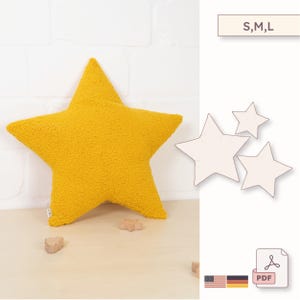 Könnte beinhalten: Ein senfgelbes kissenförmiges Sternkissen mit strukturierter Oberfläche. Das Kissen liegt auf einer hellen Holzoberfläche. Daneben befinden sich drei Sternkonturen und der Text "S,M,L".