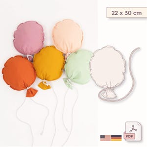 May include: Five colorful, round fabric balloons in shades of orange, yellow, pink, peach, and green, each with a white string and a small fabric bow. The image also includes a balloon template and the text "22 x 30 cm".