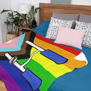 May include: A rainbow-colored fleece blanket with a graphic of a bicycle handlebar and a brown, black, pink, and blue stripe at the top.