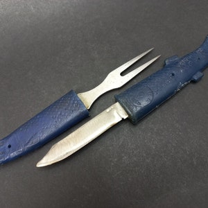 Puede incluir: Un cuchillo de bolsillo azul y plateado con forma de pez con un tenedor y una hoja. El cuchillo tiene un mango de plástico azul y una hoja de plata. El tenedor está unido al mango y se pliega en el cuchillo.