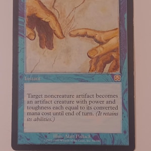May include: A Magic: The Gathering card titled "Karn's Touch" with artwork depicting two hands reaching out. The card has a blue and purple border with text describing the card's function. The artist is Alan Pollack.