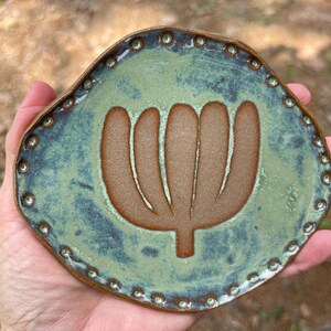 Plato ovalado de cerámica para joyas, esmalte verde con diseño botánico y borde decorado con cuentas.