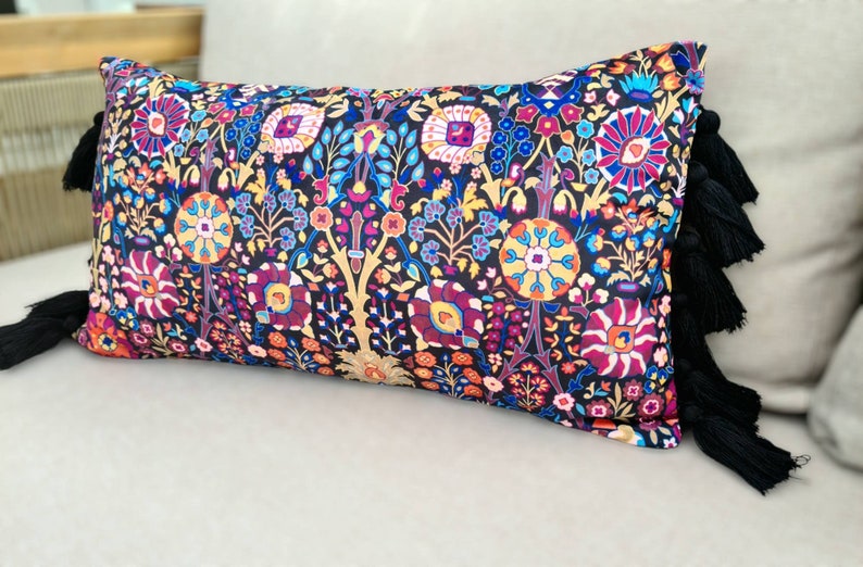 May include: A black and multi-colored patterned throw pillow with black tassel trim.