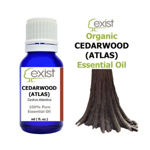May include: A blue glass bottle with a white cap, labeled "Cexist Cedarwood (Atlas) Cedrus Atlantica 100% Pure Essential Oil ml (fl. oz.)". The bottle is next to a brown tree trunk with the text "Cexist Organic Cedarwood (Atlas) Essential Oil" above it.