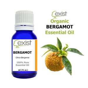 May include: A blue glass bottle with a white cap, labeled "Exist Organic Bergamot Essential Oil". The bottle is filled with a clear liquid. The label also includes the text "Citrus Bergamia" and "100% Pure Essential Oil". A bergamot fruit with green leaves is shown in the background.