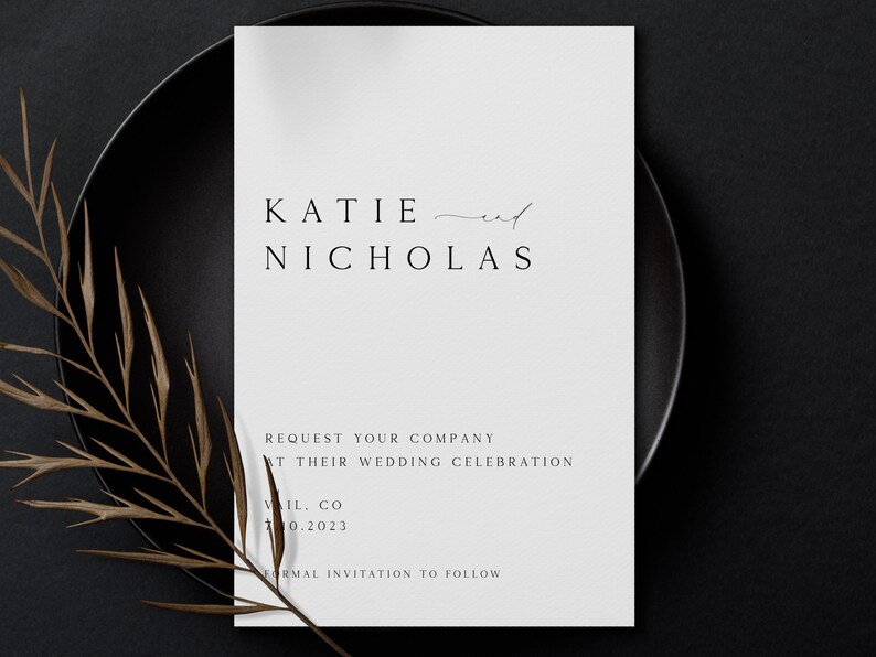 May include: A white wedding announcement card with black text. The card reads "KATIE and NICHOLAS REQUEST YOUR COMPANY AT THEIR WEDDING CELEBRATION VIL. CO 10.2023 FORMAL INVITATION TO FOLLOW."