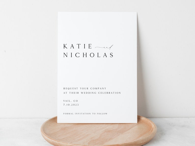 May include: A white save the date card with black text announcing the wedding of Katie and Nicholas. The card states "Request your company at their wedding celebration" and includes the date and location: Vail, CO 7.10.2023. The card also states "Formal invitation to follow."