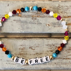 May include: A colorful beaded bracelet with gold beads and letter beads spelling "BE FREE". The beads are in a rainbow pattern of red, orange, yellow, green, blue, and purple.