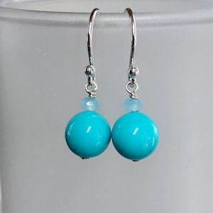 Op de afbeelding: Turquoise blauwe glazen kralen oorbellen met zilveren haakjes en kleine lichtblauwe accent kralen.