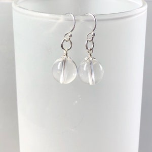 May include: A pair of silver dangle earrings with clear glass sphere beads.