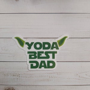 May include: White sticker with green text that reads "Yoda Best Dad" with green ears on either side of the text.