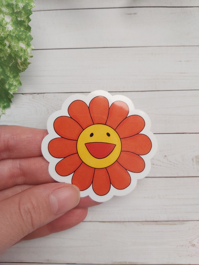 以下が含まれることがあります： 笑顔の顔が付いた赤と黄色の花のステッカー。花は白い輪郭で、白い背景になっています。