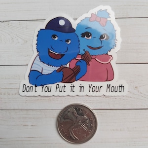 May include: A sticker featuring two blue fuzzy characters with big eyes and smiles. The characters are holding a brown guitar and the sticker says "Don't You Put it in Your Mouth".