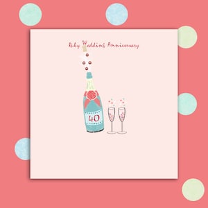May include: A pink card with a champagne bottle and two glasses. The bottle has a red bow and the number 40 on it. The text "Ruby Wedding Anniversary" is at the top of the card.