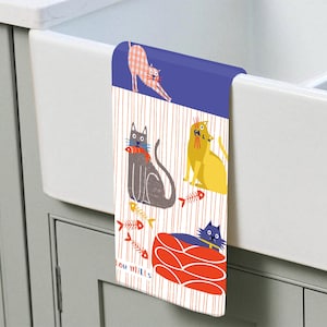 May include: A kitchen towel featuring a whimsical cat design. The towel has a blue top and a striped background with illustrations of cats, fish bones, and a red cat bed. The cats are in various poses and colors, adding a playful touch to the kitchen.