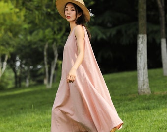 May include: A woman wearing a pink sleeveless maxi dress and a straw hat walks on a grassy lawn.