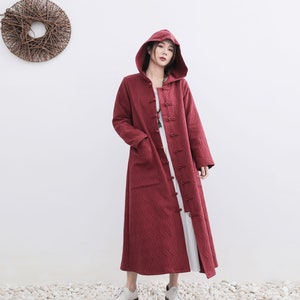 May include: A long, red hooded coat with a quilted pattern and a button closure. The coat has a relaxed fit and is made of a soft, comfortable fabric.