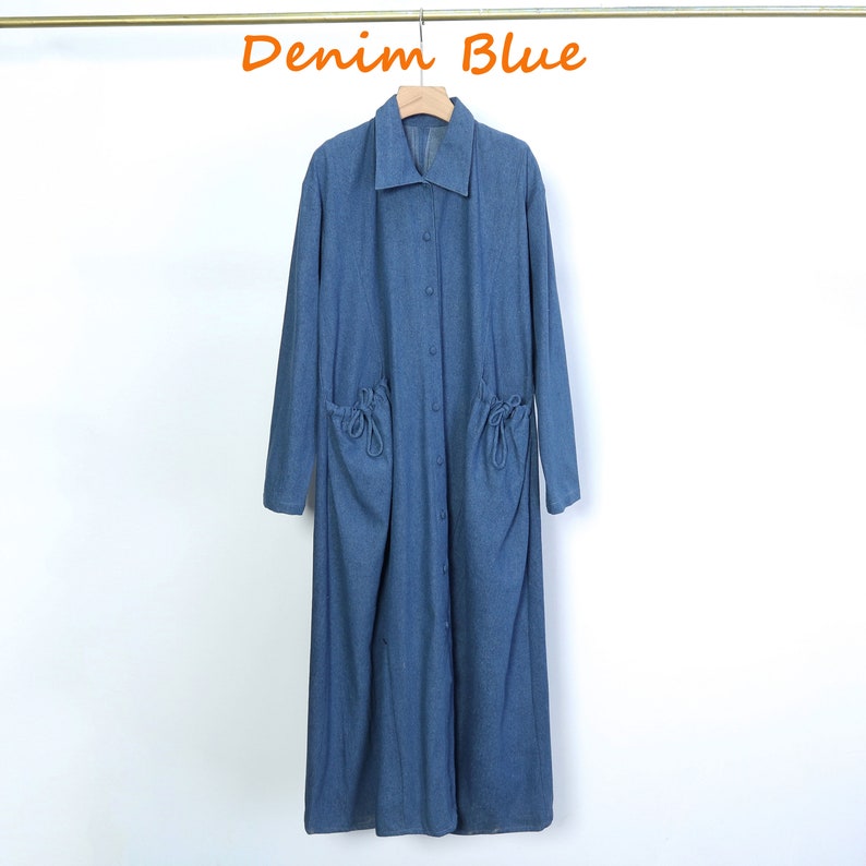 May include: A long-sleeved denim shirt dress with a collared neckline and button fastening. The dress has two large pockets with drawstring closures on the front.