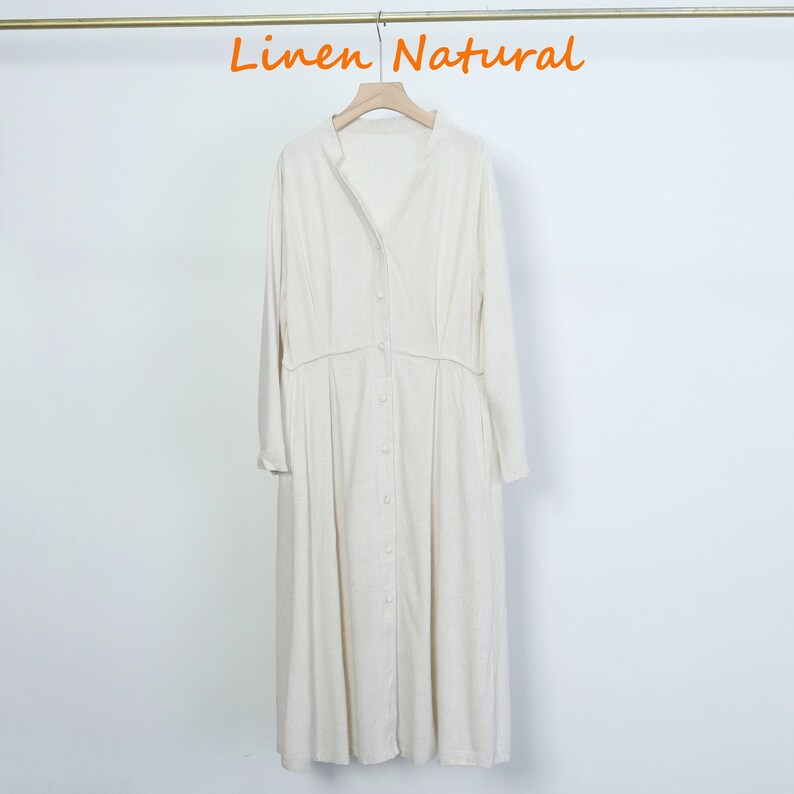 Puede incluir: Vestido largo de lino blanco roto con mangas largas y abotonadura frontal. El vestido tiene cuello mandar&iacute;n y cintura fruncida. El texto "Linen Natural" est&aacute; en naranja en la parte superior.